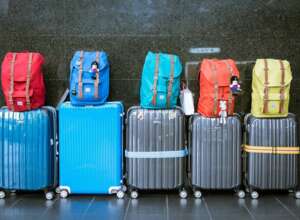Blaue und graue Koffer mit bunten Rucksäcken oben drauf