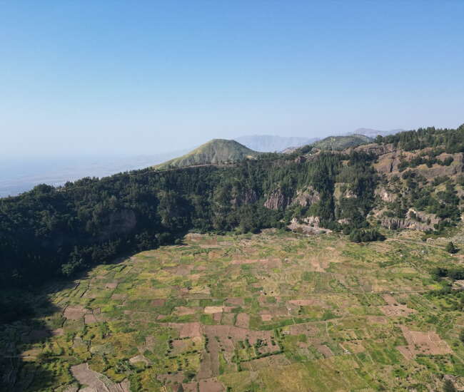 Grüne Felder in einer weiten vulkanischen Berglandschaft